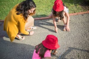 Kinderen die met een pedagogisch medewerkster met een flexibele baan in de kinderopvang aan het buiten spelen zijn.