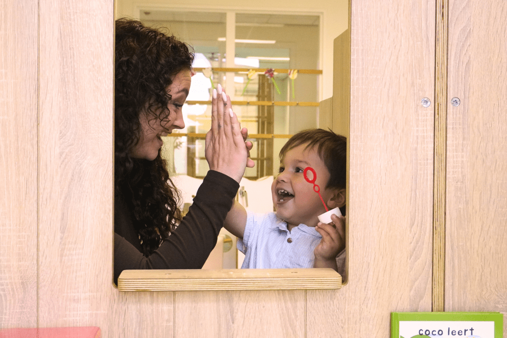 Kind geeft pedagogisch medewerker high five