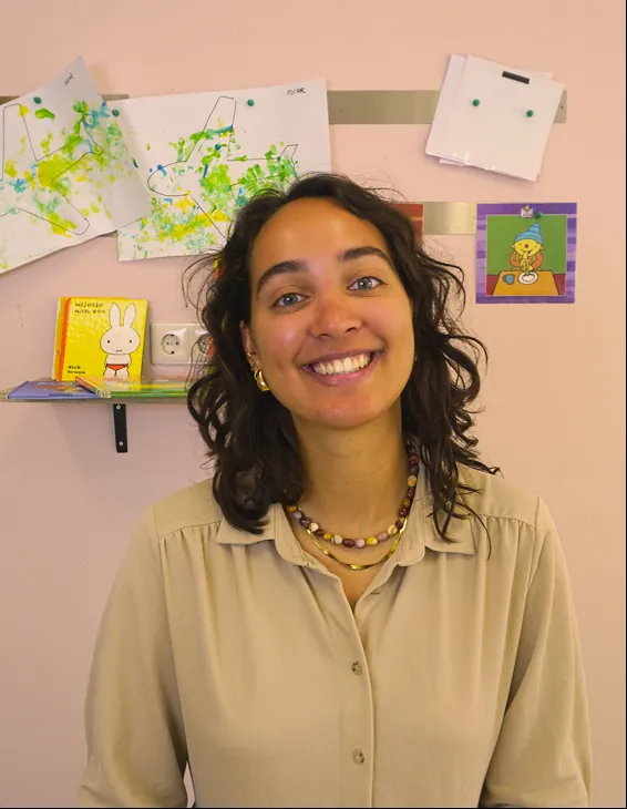 Lachende pedagogisch medewerker voor een muur met kindertekeningen